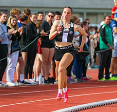 Jeune fille qui court sur une piste d'athlétisme accompagnée du public, cours avant de donner le relais à sa partenaire